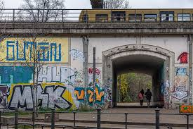 A train crossing above a graffiti-covered railway underpass in Berlin.
