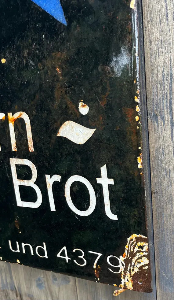 The word Brot on a chipped, black enamel bakery sign.