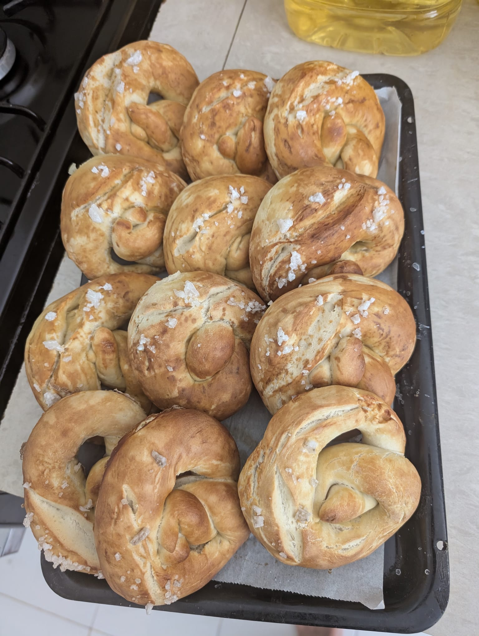 Hand-shaped pretzels sprinkled with coarse salt on a baking tray.